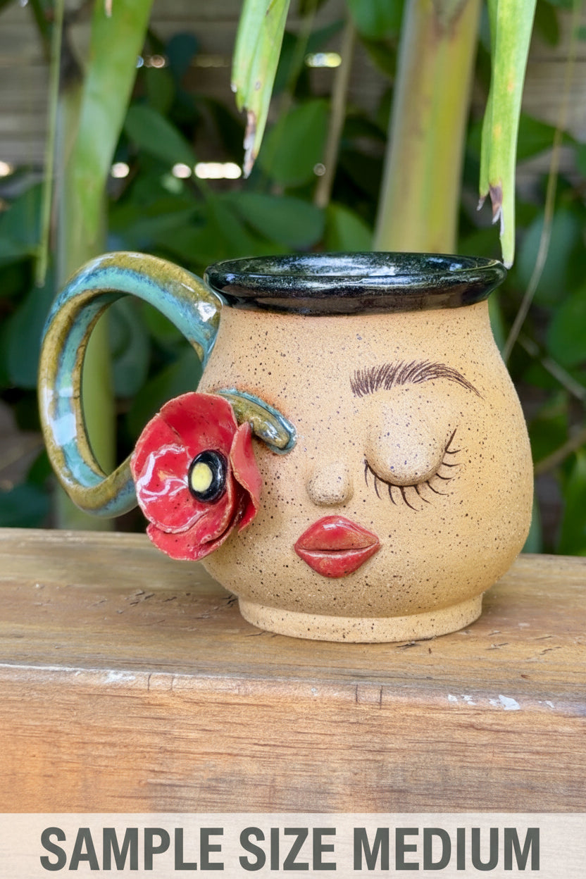 Ceramic mug with face design and red flower on a wooden surface